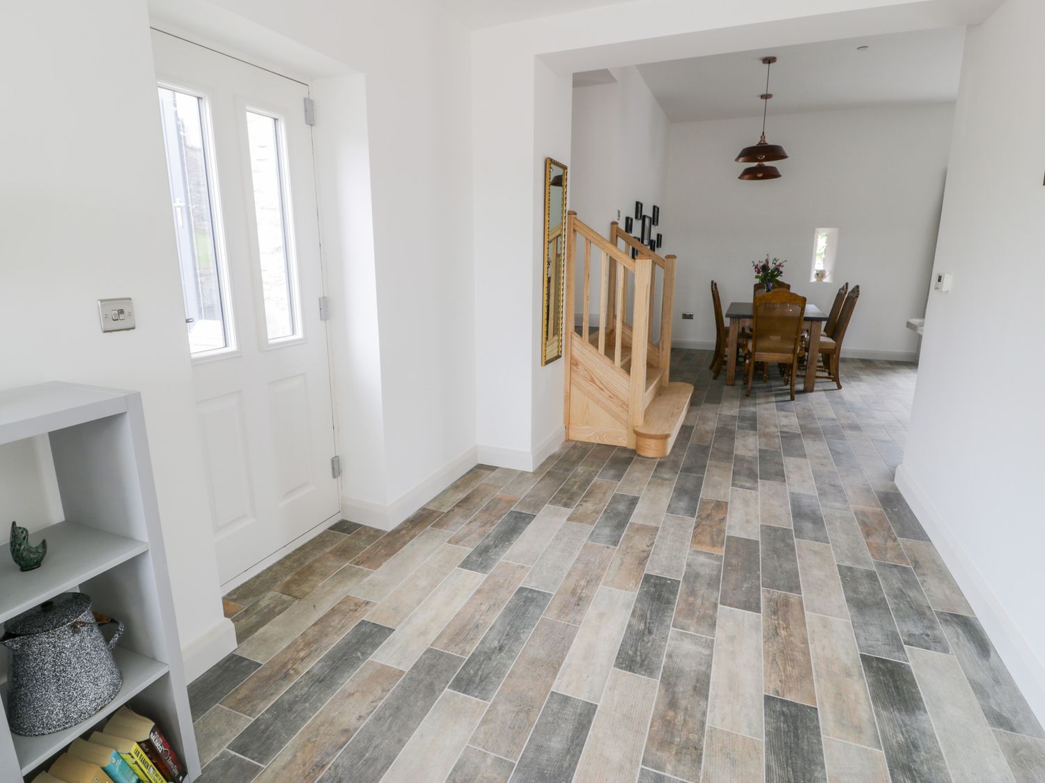 A hallway with a staircase next to a dining area with a table and chairs at Storws in Pentraeth