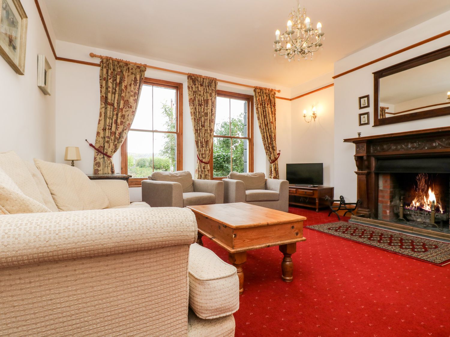 A living room with sofas coffee table fireplace and television at Penare House in Mevagissey