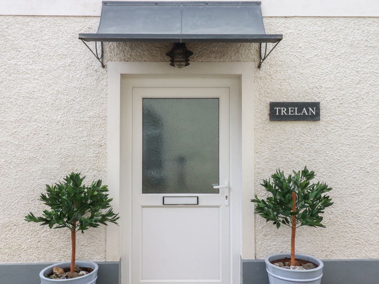 An entrance with a door and potted plants at Trelan in Mevagissey