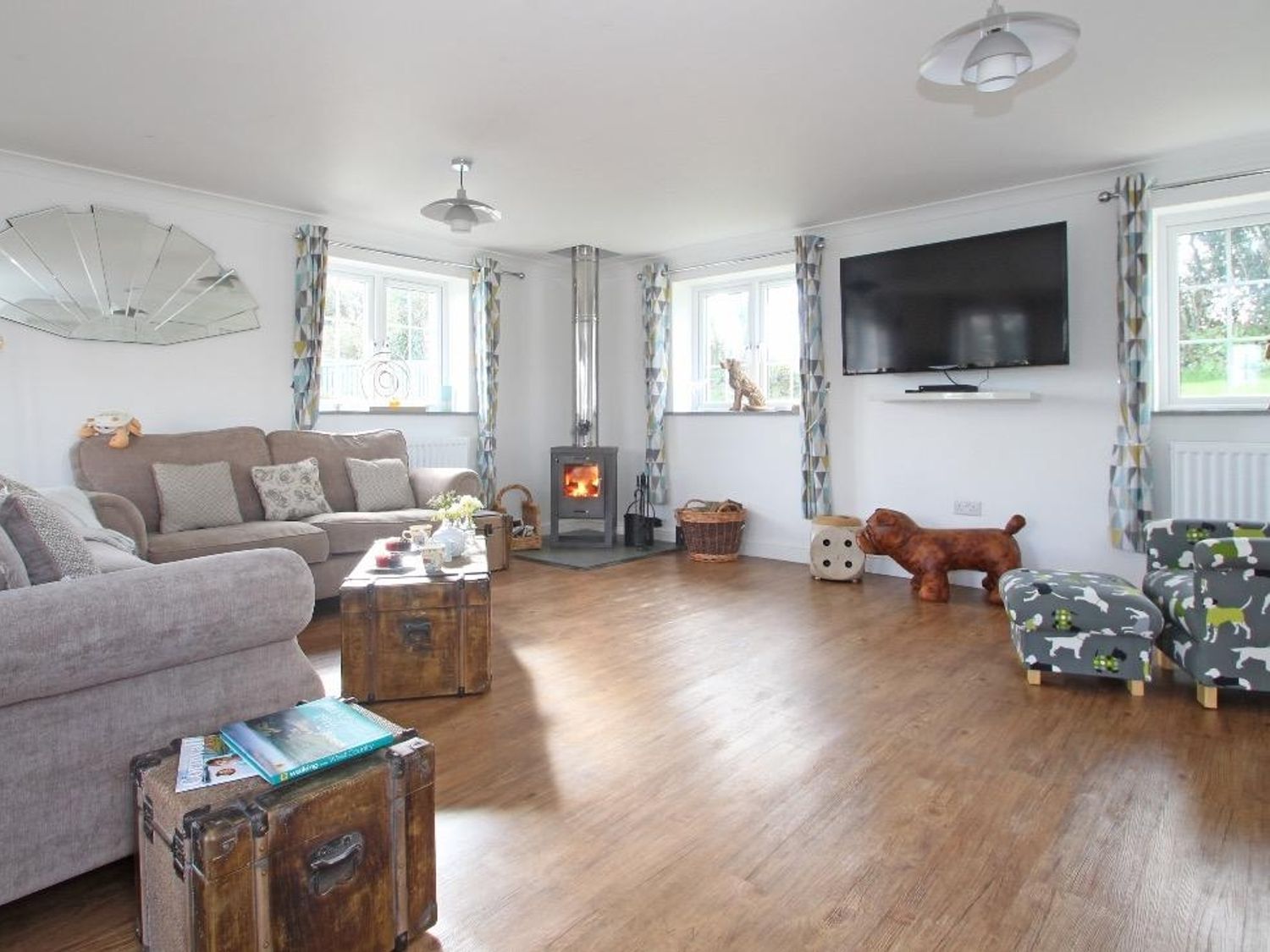A living room with a wood stove television two sofas patterned curtains and wooden floors at Omalast in Chacewater near Truro