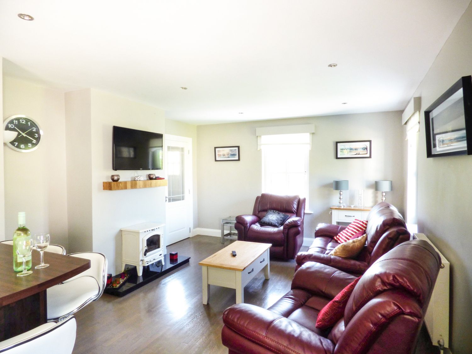 A living room with leather sofas a coffee table a wall mounted TV and a small stove at Hidden Gem Cottage in Lettermacaward near Dungloe County Donegal
