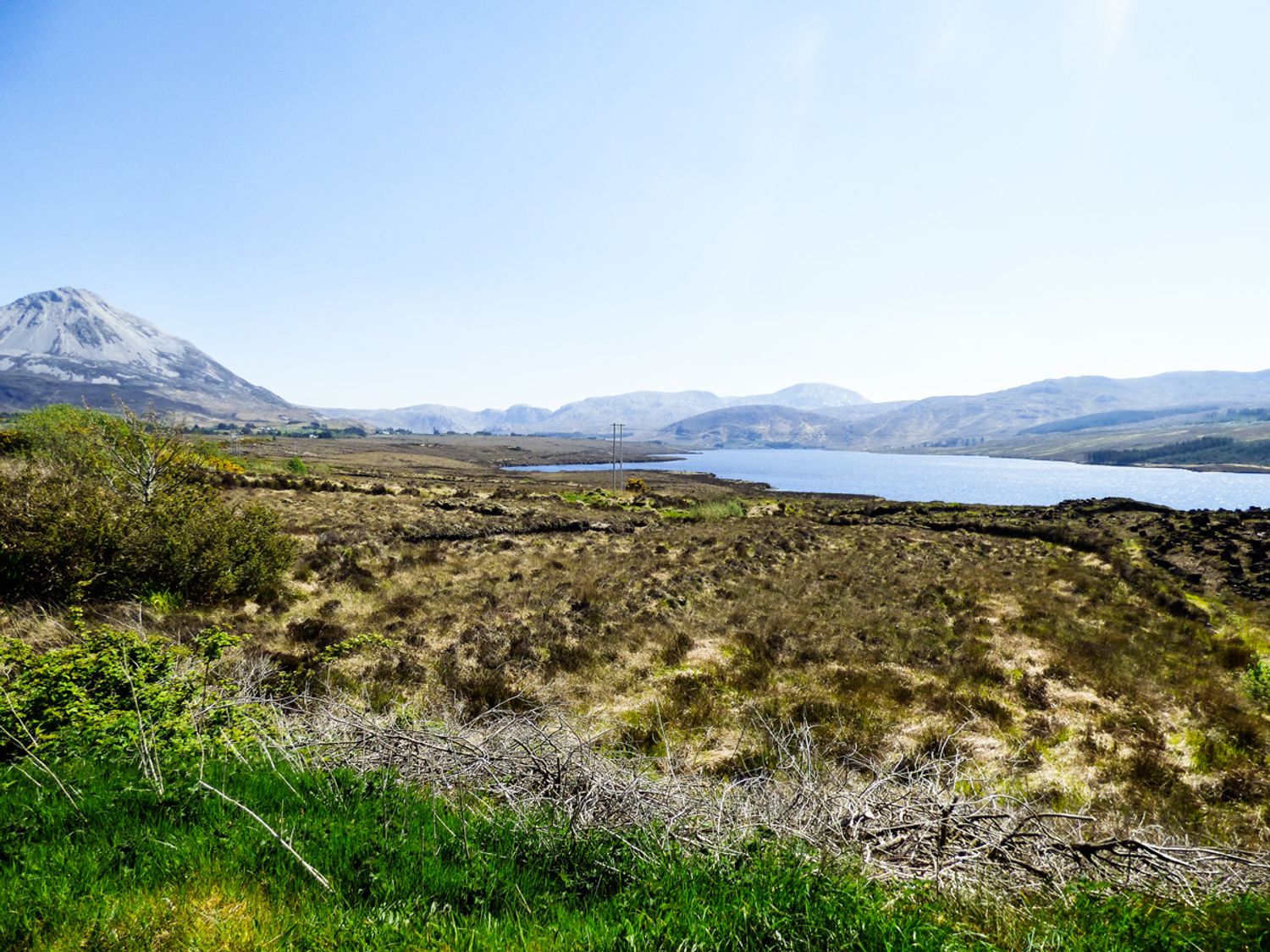 A landscape with a grassy field a body of water and mountains in the background at Hidden Gem Cottage in Lettermacaward near Dungloe County Donegal