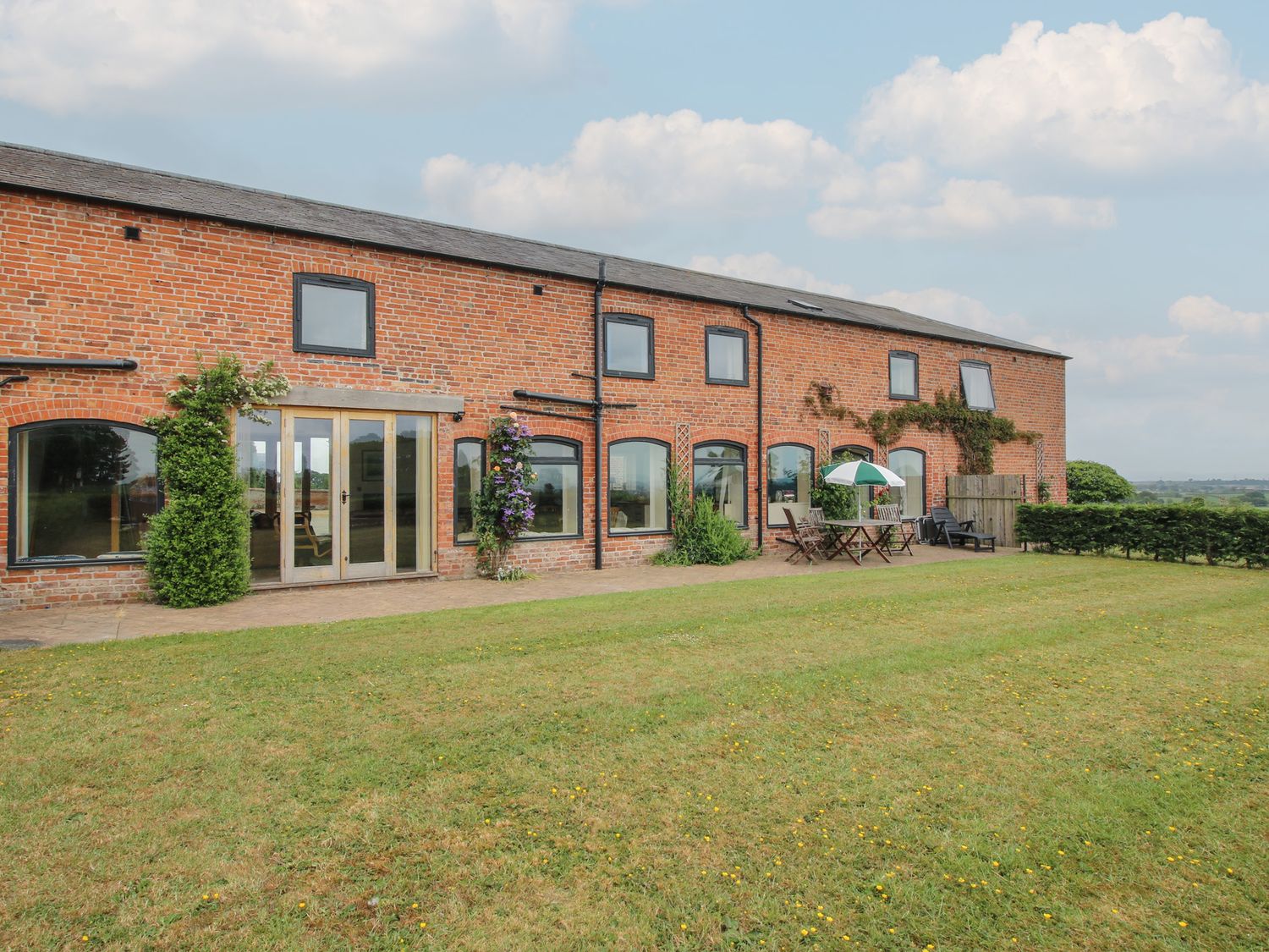 An outdoor view of a brick building with patio furniture at The Oaks Cockshutt near Ellesmere