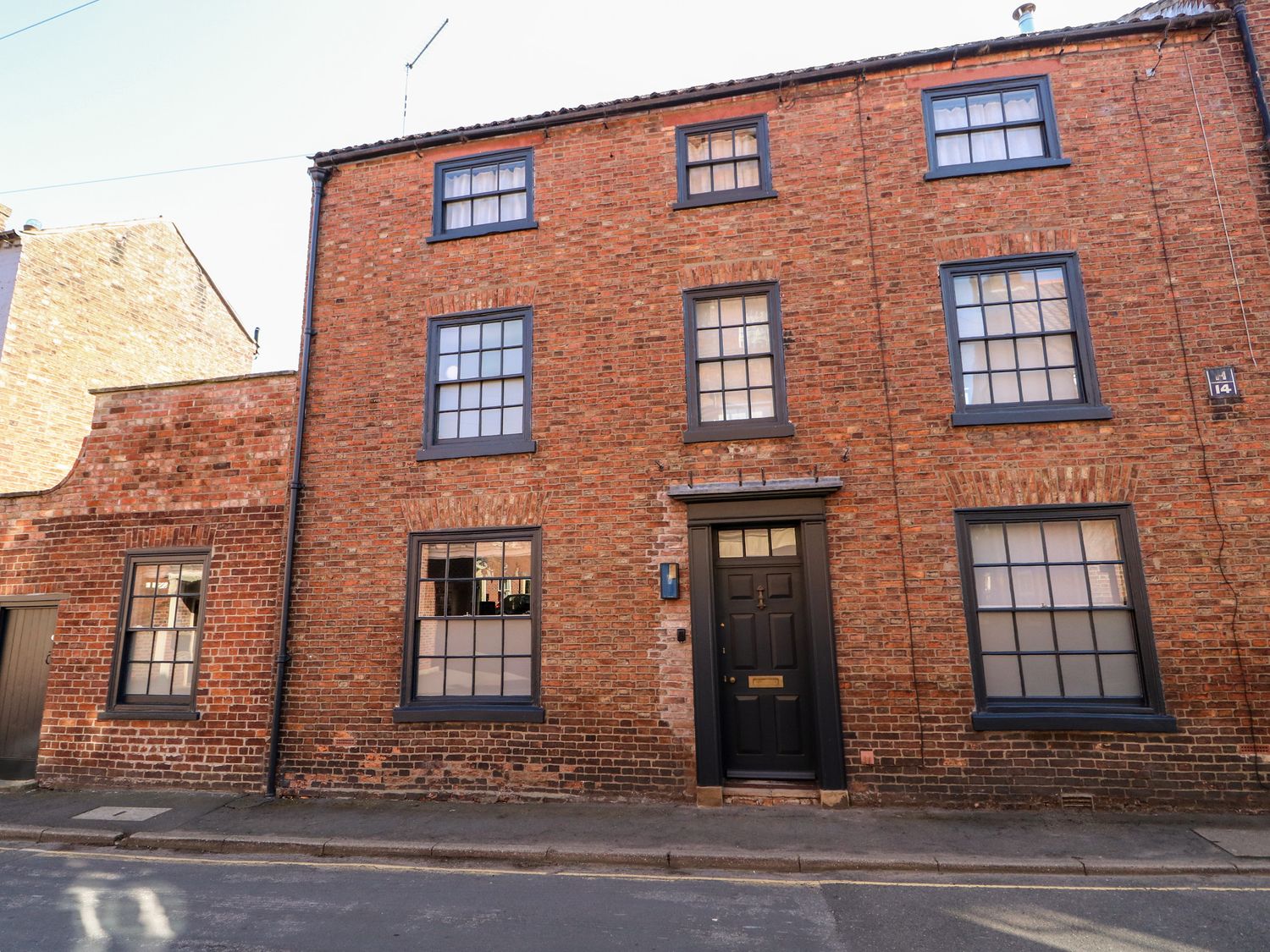 A brick building with several windows and a black door on a street at 12 Banks Street in Horncastle
