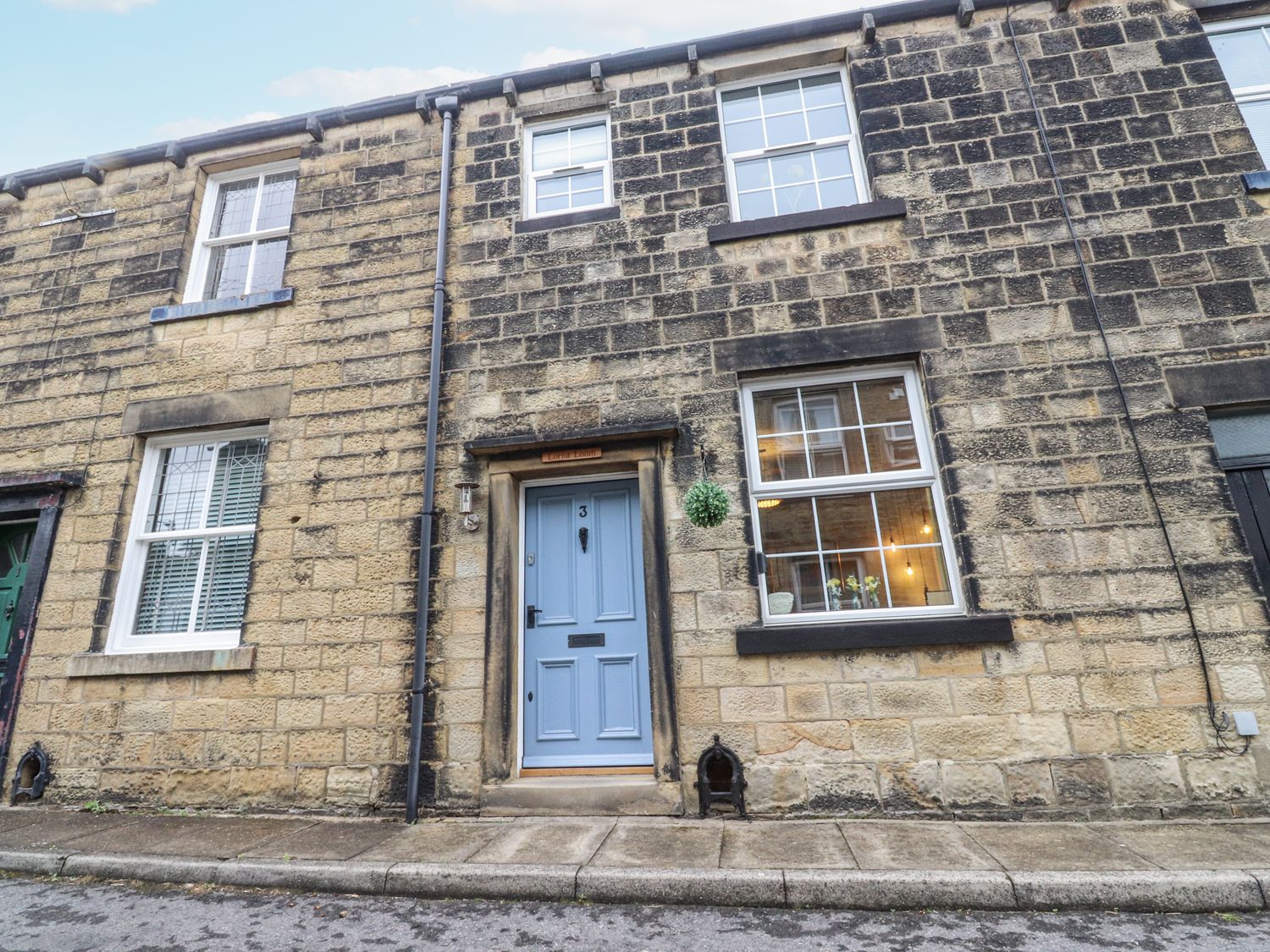 A front view of a house with a blue door and windows at Lorna Loom in Skipton