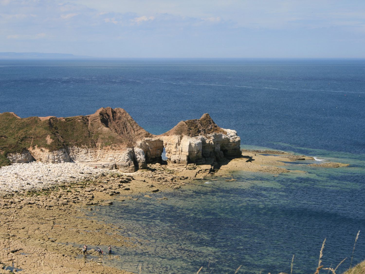 A rocky coastal area with cliffs and clear sea water at Pebble Cottage Dunnscroft in Flamborough