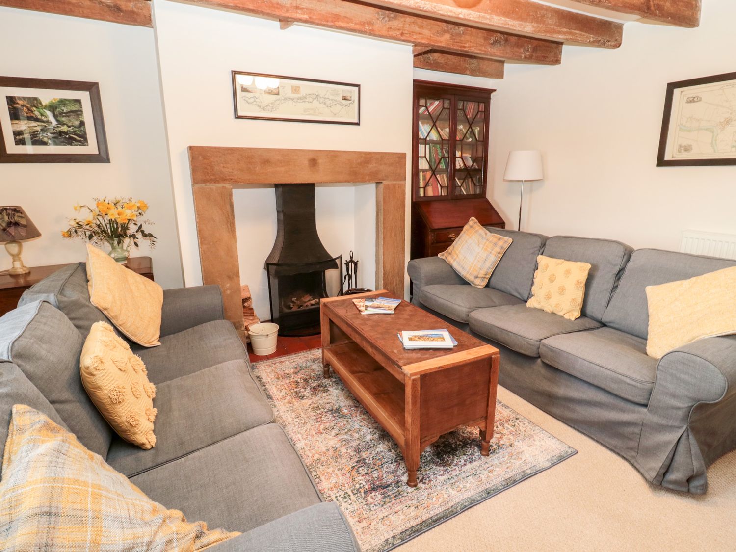A living room with two gray sofas and a wooden coffee table in front of a fireplace at 2 Redeswood Cottages in Bellingham