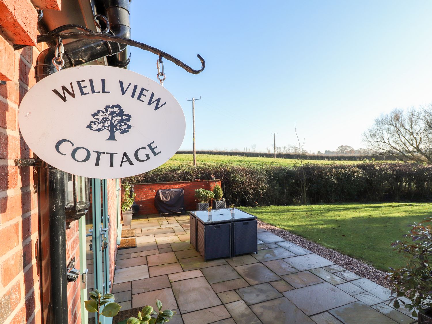 A patio with outdoor furniture and a garden outside Well View Cottage in Chester