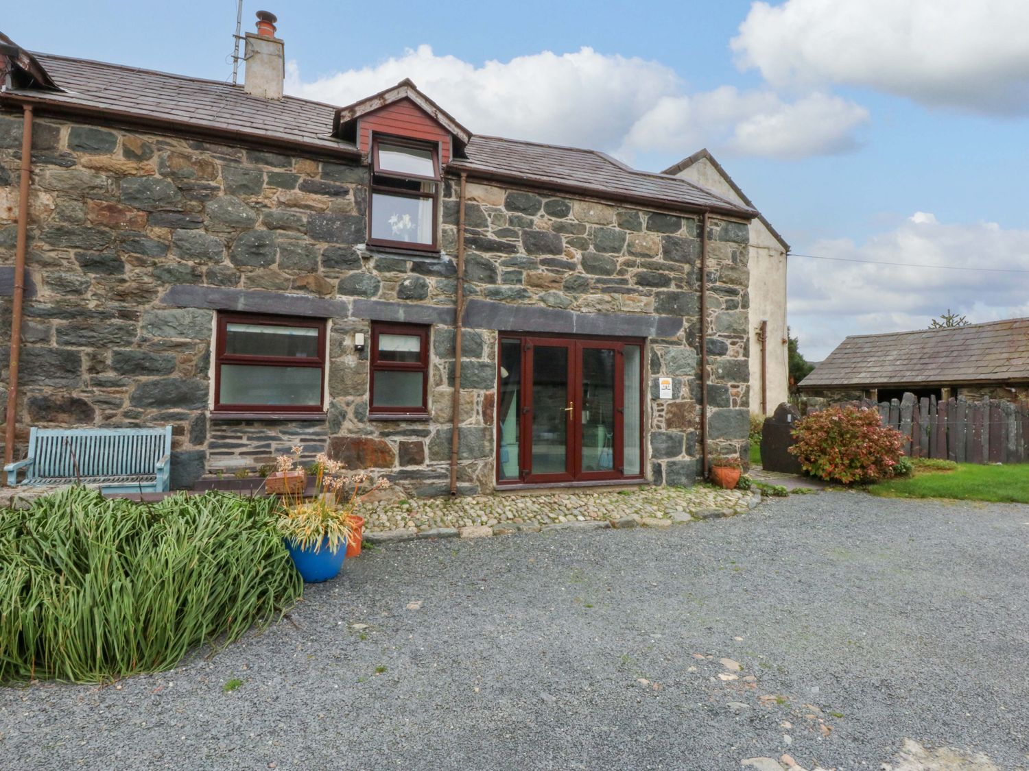 An outdoor view of a stone building with a bench at Hafod in Y Felinheli