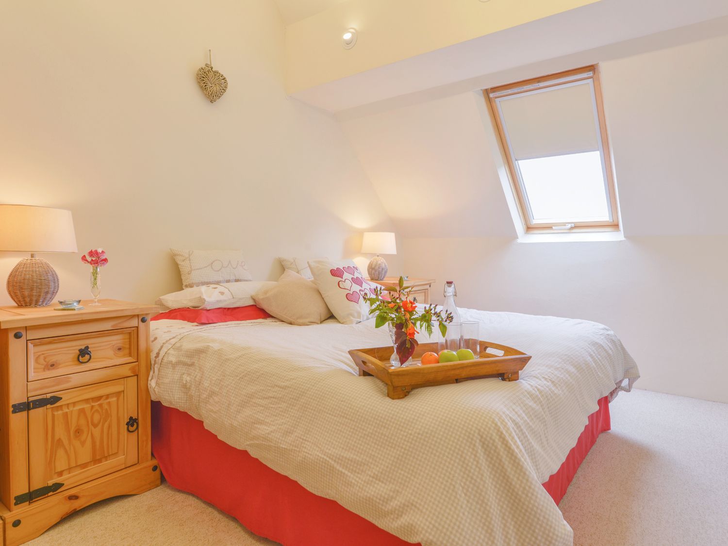 A bedroom with a bed tray holding flowers and fruit beside a slanted window at The Bolthole in Throwleigh near Chagford