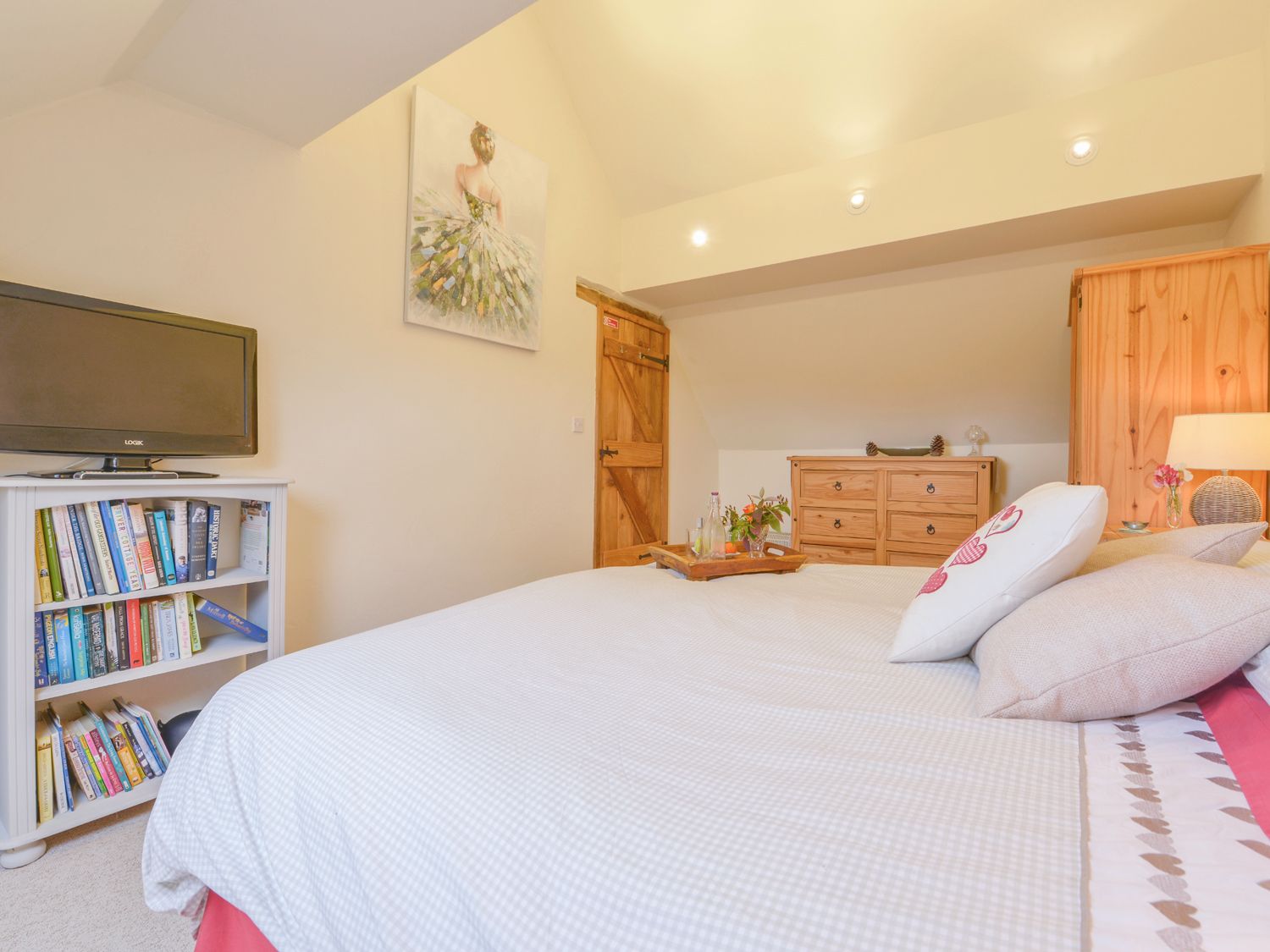 A bedroom with a bed bookshelf television wooden door and wooden dresser at The Bolthole Throwleigh near Chagford