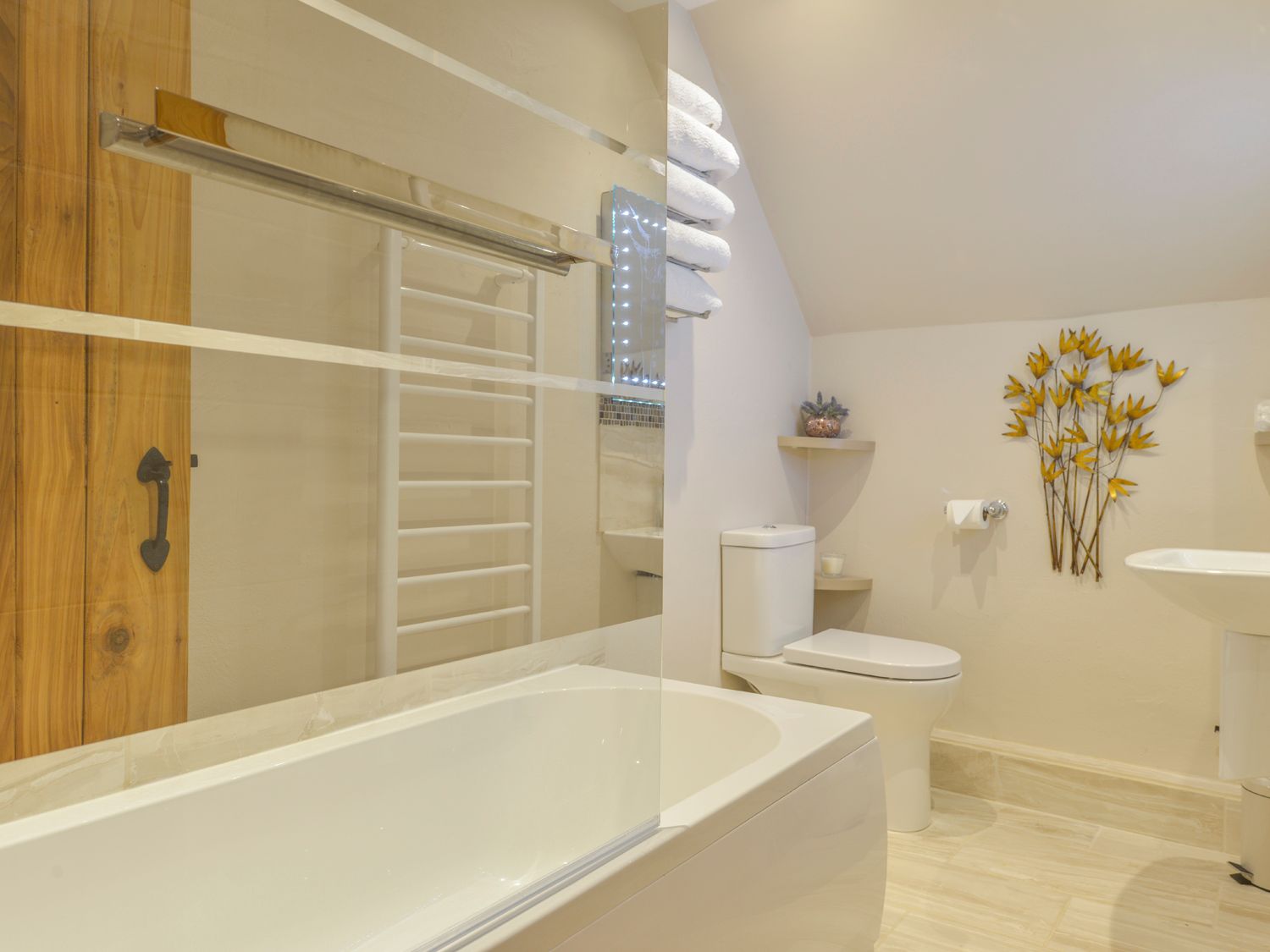 A bathroom with a bathtub glass shower screen toilet wall decoration and towel shelf at The Bolthole in Throwleigh near Chagford