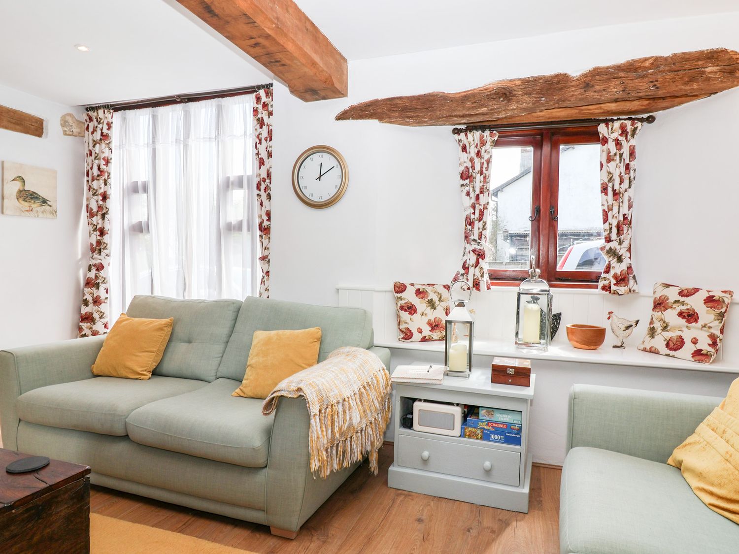 A living room with two sofas a side table and floral curtains at The Bolthole in Throwleigh near Chagford