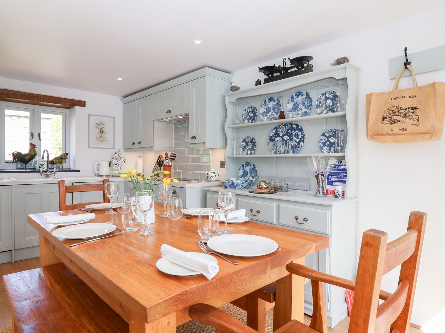 A kitchen dining area with a wooden table set for four and blue and white plates on shelves at The Bolthole in Throwleigh near Chagford