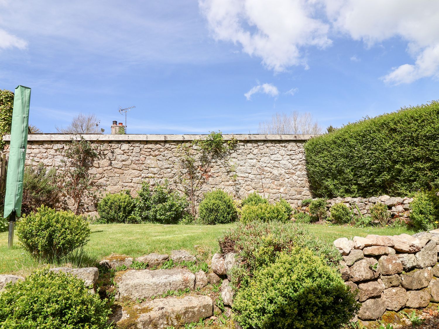 A garden with stone steps bushes and a stone wall at The Bolthole in Throwleigh near Chagford