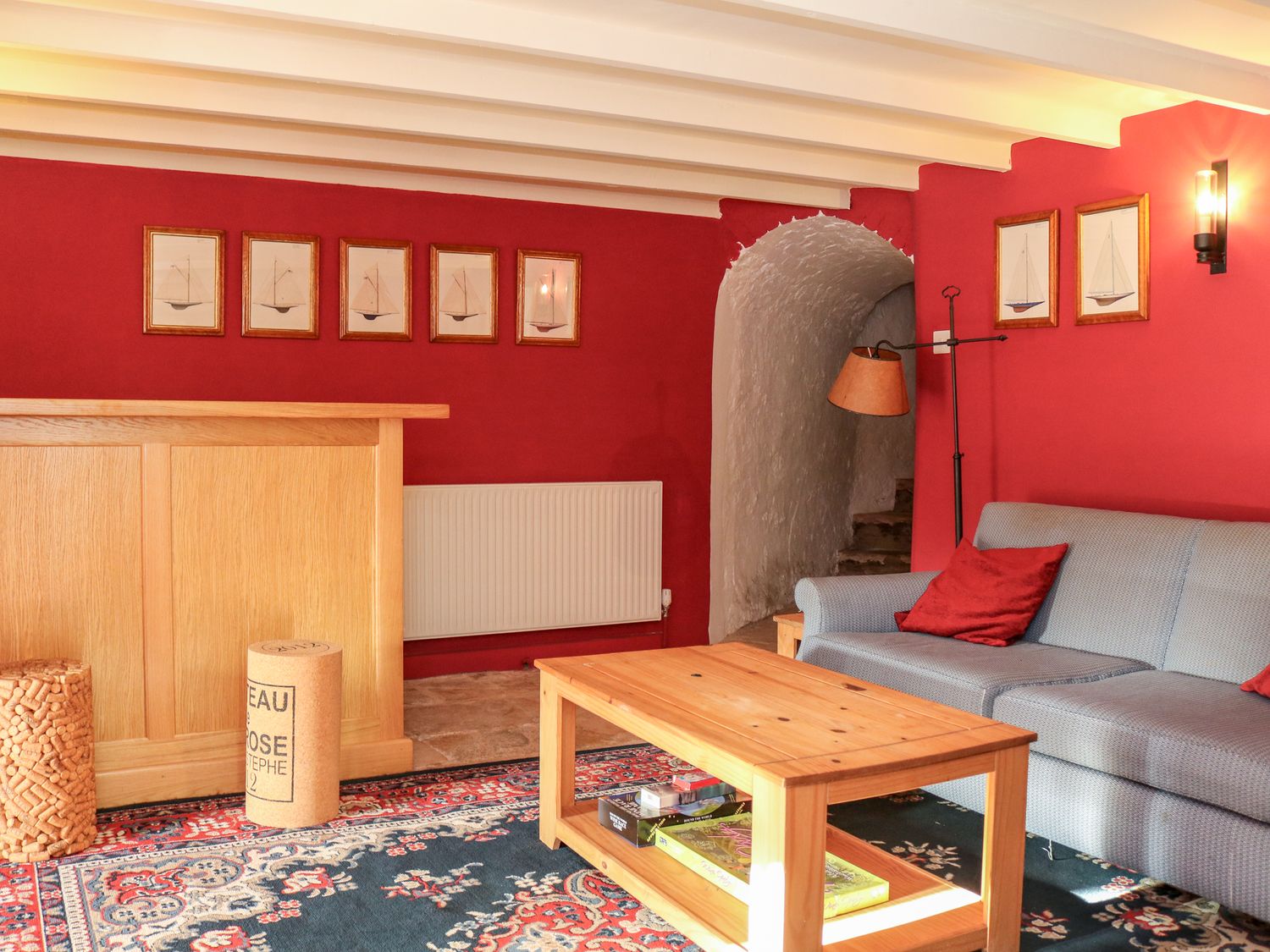 A living room with a wooden coffee table gray sofa and red walls at Sandridge Barton in Stoke Gabriel