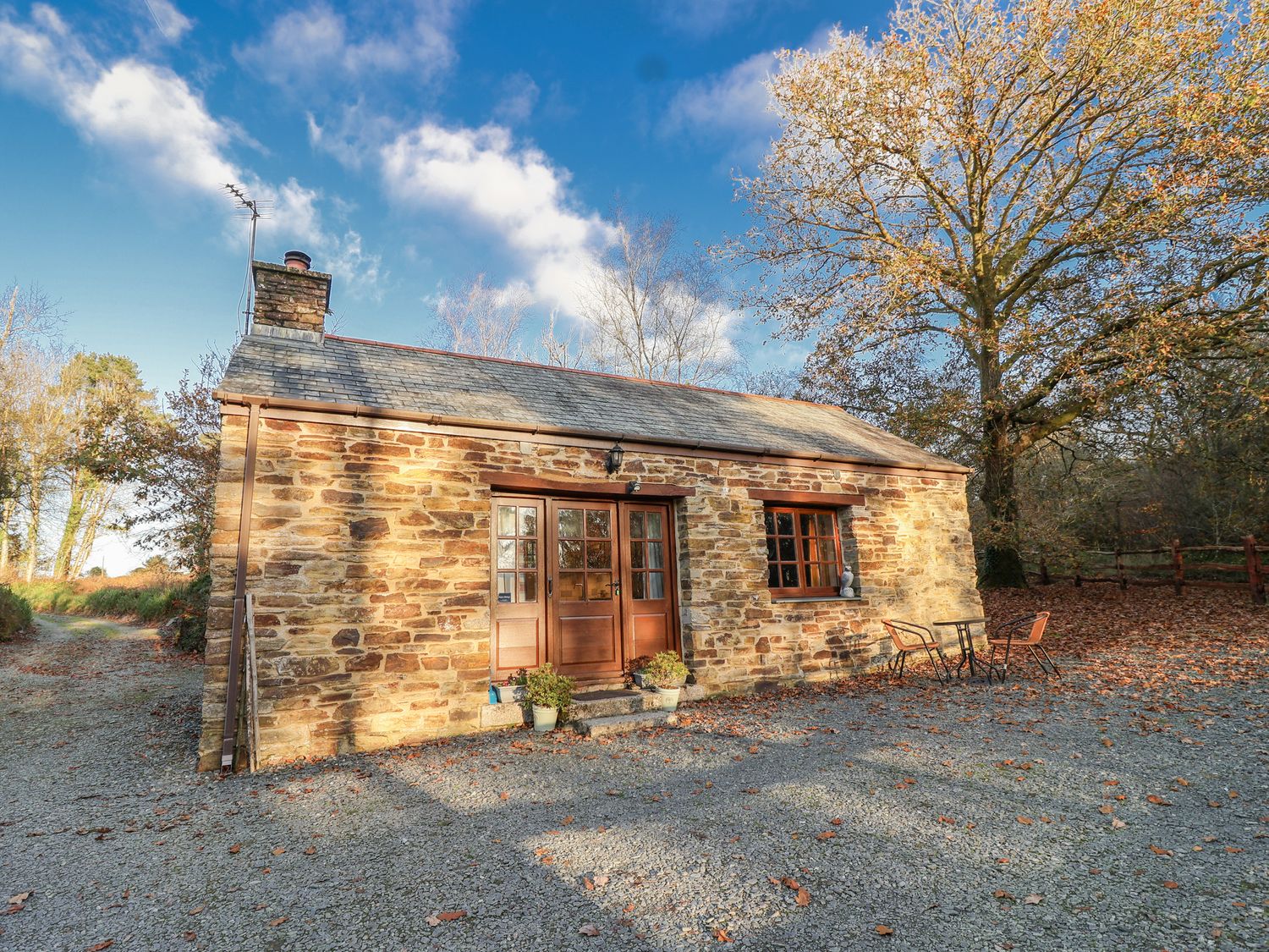 A cottage with a gravel driveway and outdoor seating at Miners Dry in Gulworthy, near Tavistock