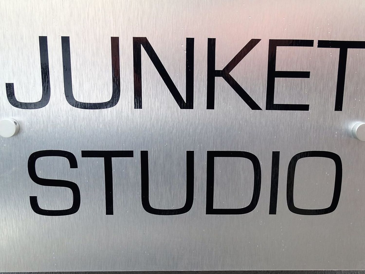A metal sign with black letters reading Junket Studio