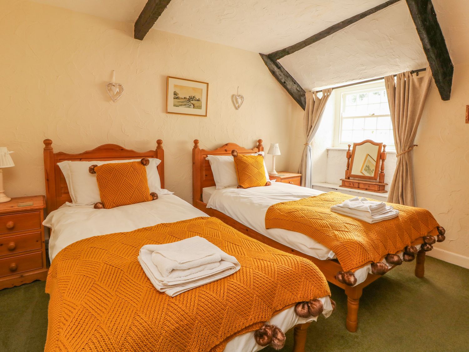 A bedroom with two single beds with orange blankets and pillows at Cousham Cottage in Kingsand And Cawsand