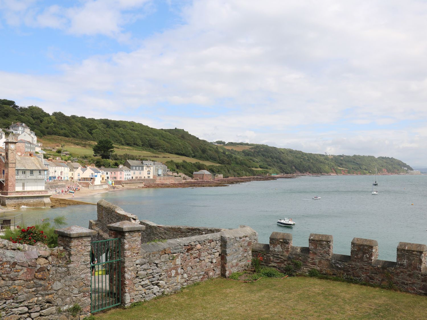 A coastal view with a stone wall and gate overlooking water boats and a village at Cousham Cottage in Kingsand And Cawsand