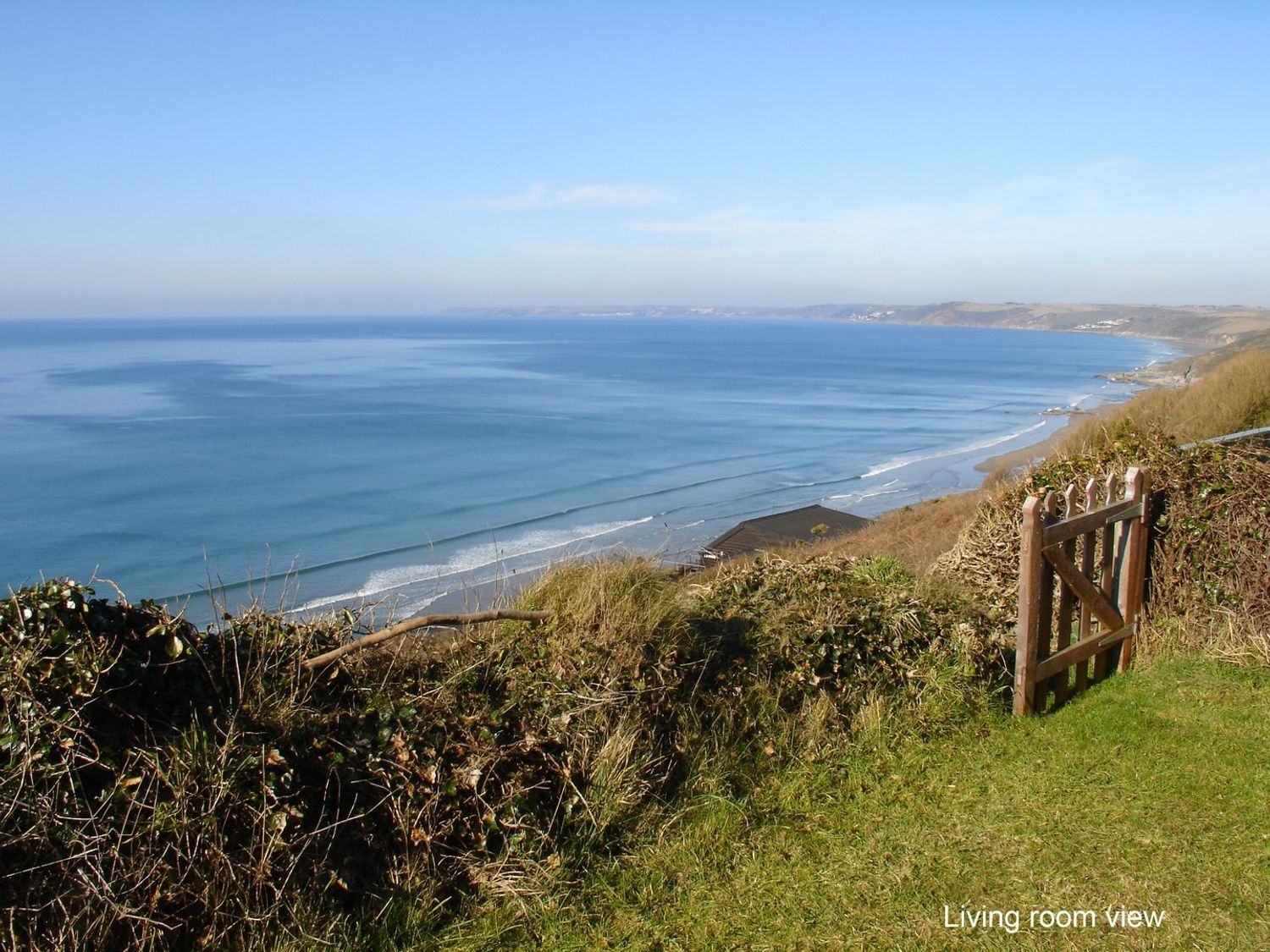 A coastal view from a grassy area with a wooden gate overlooking the sea at Seagulls Nest Whitsand Bay near Millbrook