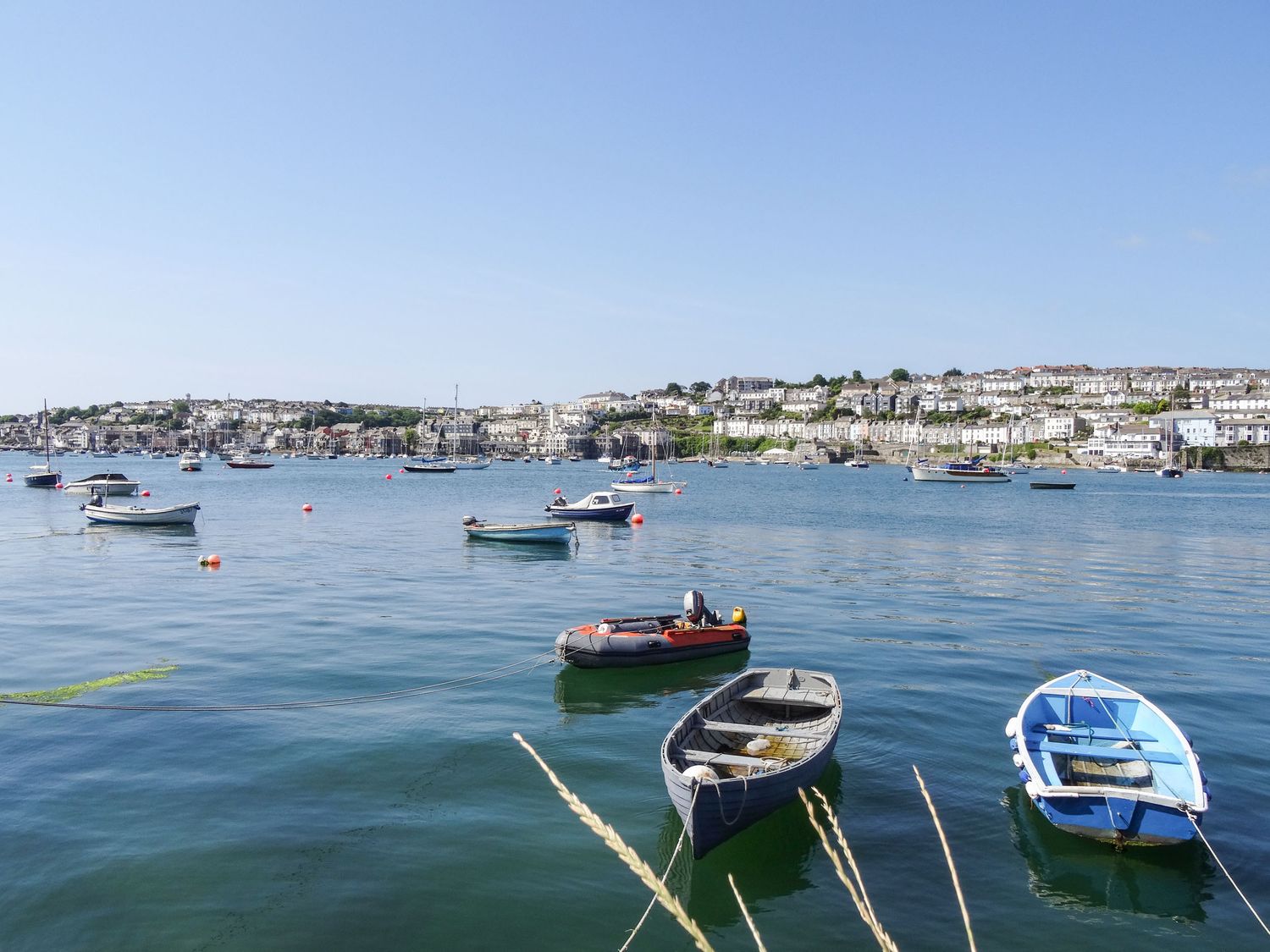 A harbor with several boats on the water and a town in the background at Quarry Cottage in Flushing near Falmouth