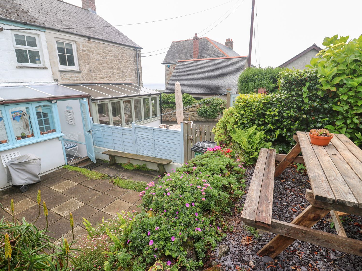 A garden with flowers and a wooden bench at 2 The Cottages Ludgvan