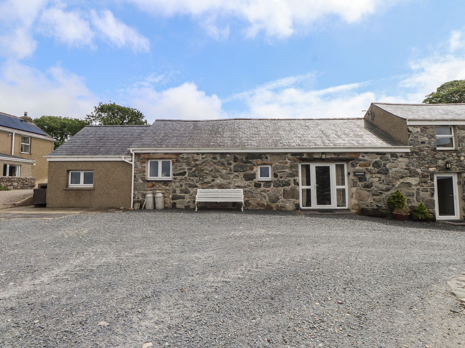 An outdoor area with a stone building and a bench at Coetsiws in Clynnog Fawr