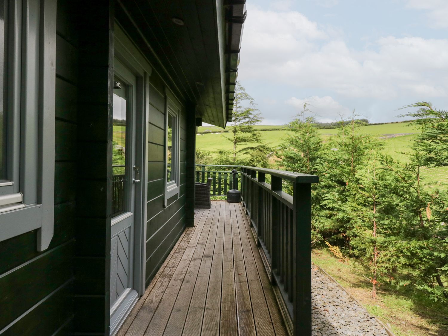 An outdoor area with a deck and trees at Oak Lodge in Pennington near Ulverston