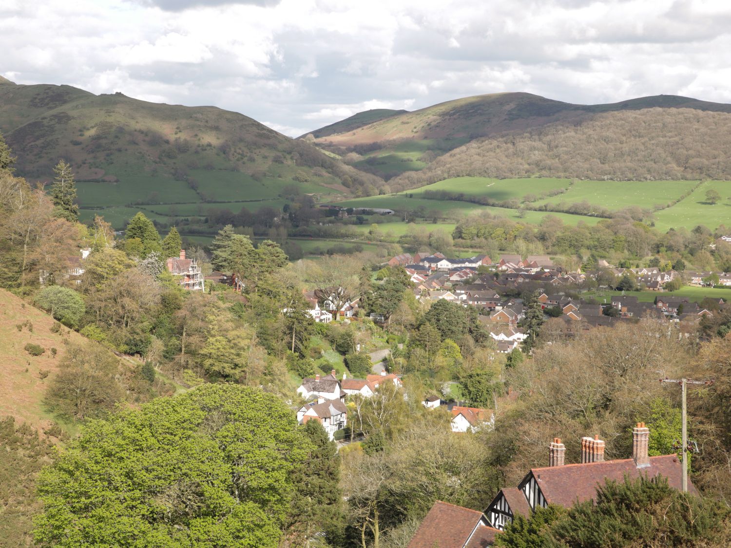 A village with houses and trees surrounded by hills and greenery at The Dovecote in Craven Arms