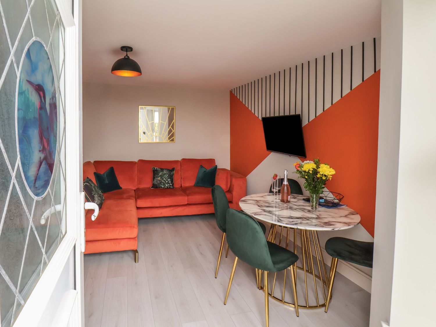 A living room with orange sofa green chairs and a round marble dining table at Apt 2 Hunter's Quay in Bridlington