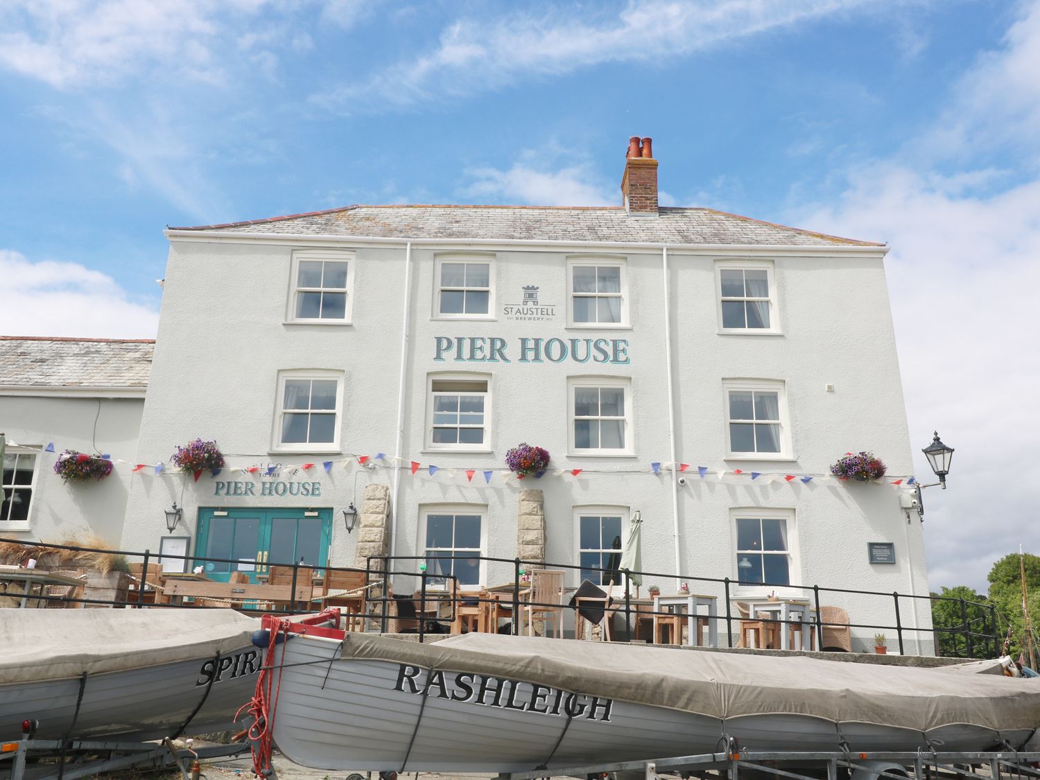 The exterior of Pier House with boats named Spirit and Rashleigh in front at Little Pippin in Carlyon Bay near St Austell