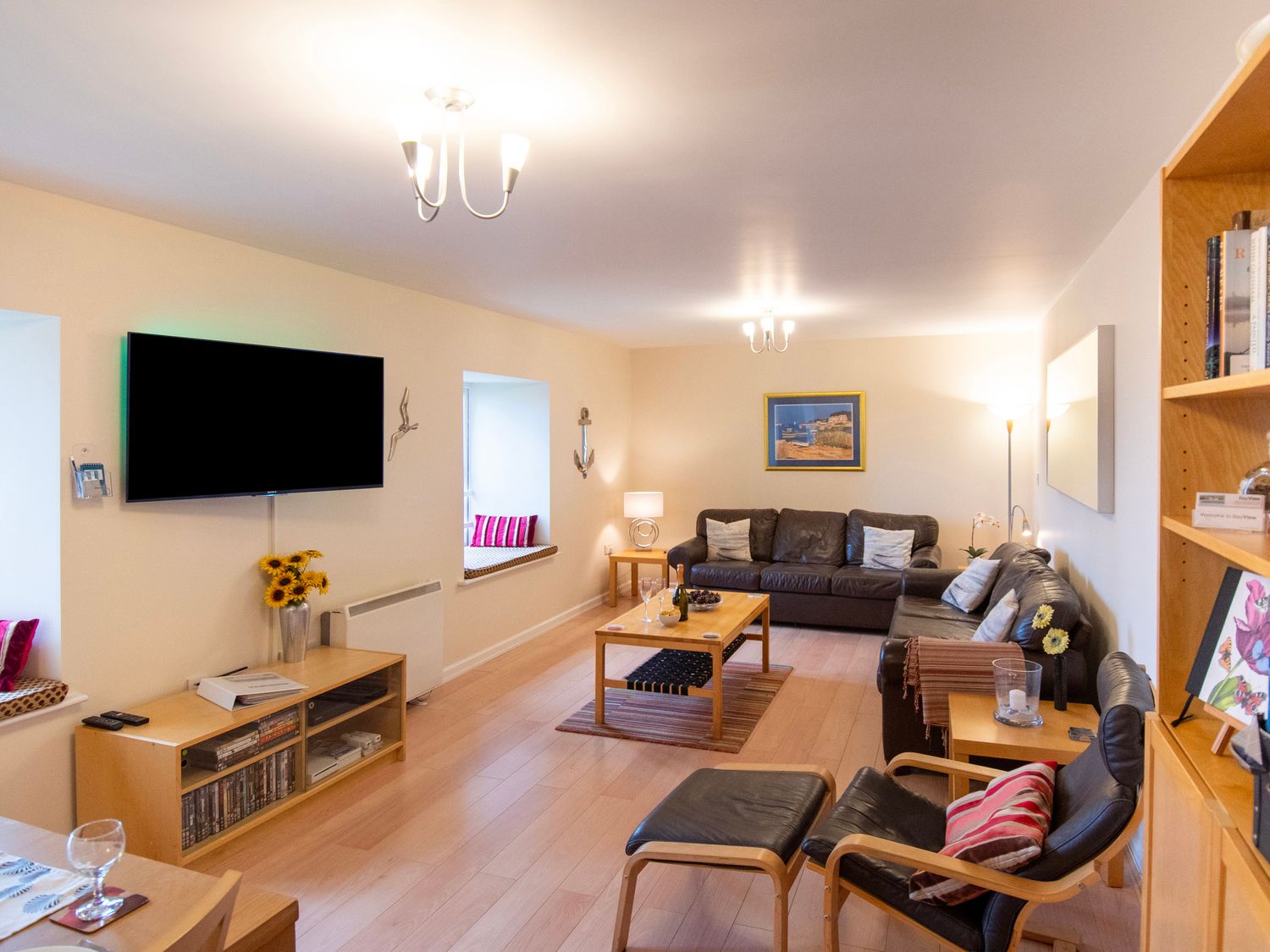 A living room with black leather sofas a wooden coffee table and a wall mounted TV at Bay View Waren Mill near Bamburgh