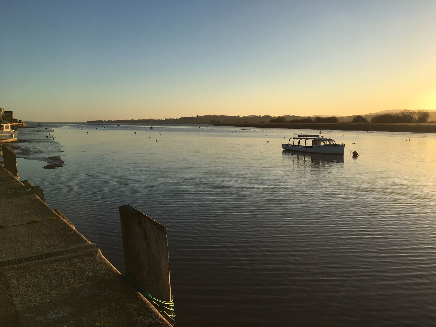 A river with a boat anchored near the shore and a concrete pier at Upham View in Woodbury