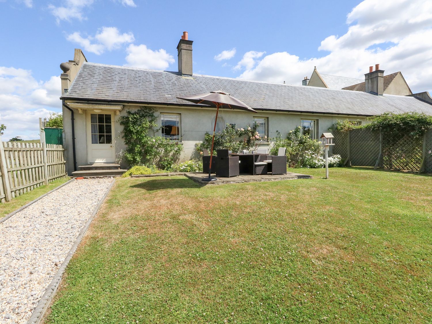 A garden with furniture and a parasol at Maple Cottage Buckland Newton near Dorchester