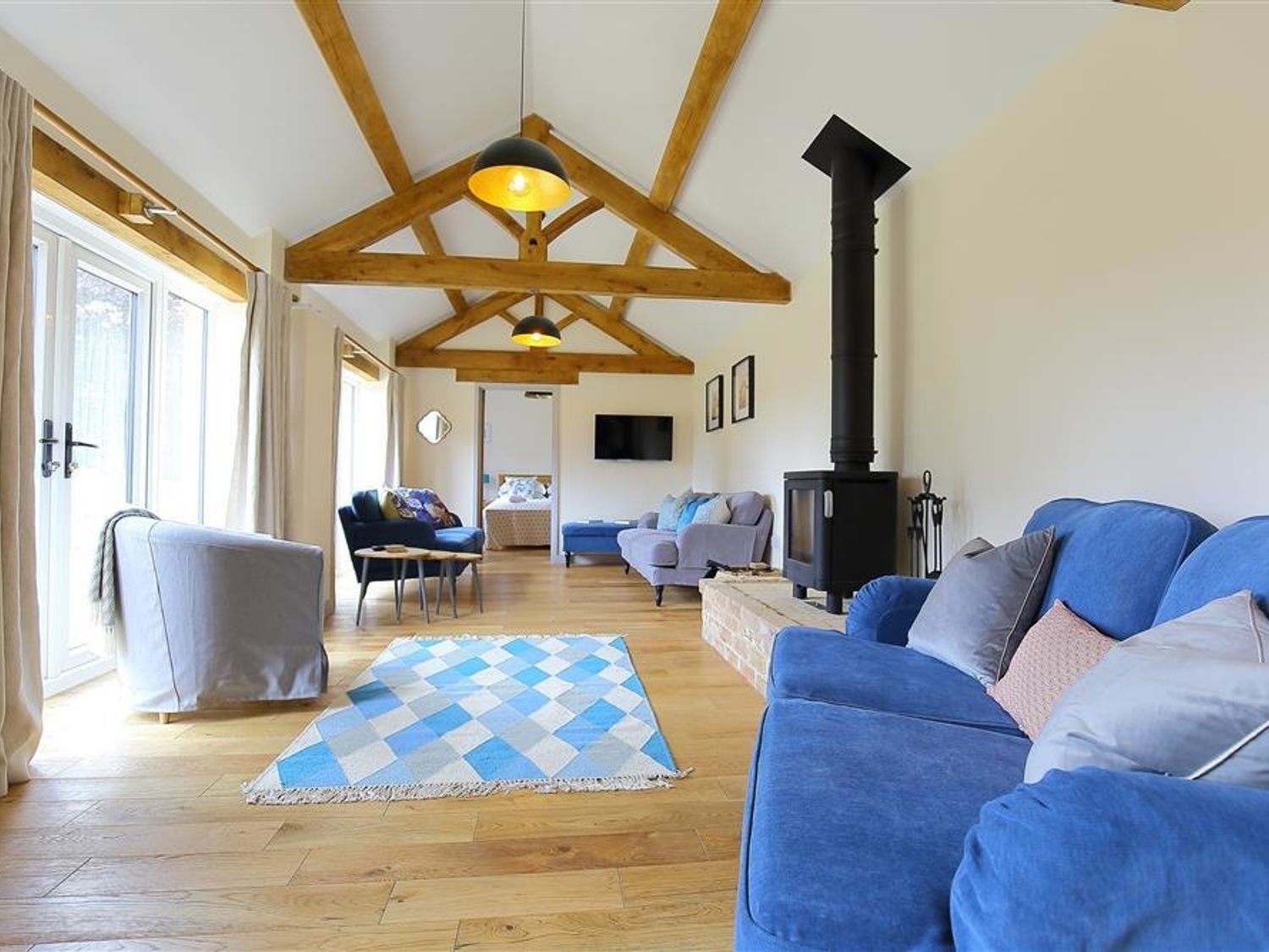 A living room with sofas a wood burning stove and exposed wooden beams at Park Stables Wyck Beacon near Bourton-on-the-Water