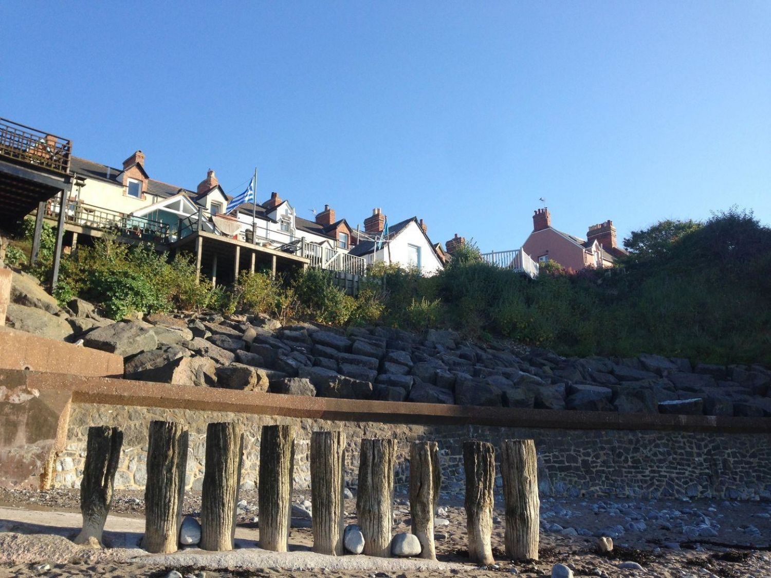 A row of houses on a hillside above wooden posts on a rocky beach at Anchorage Watchet
