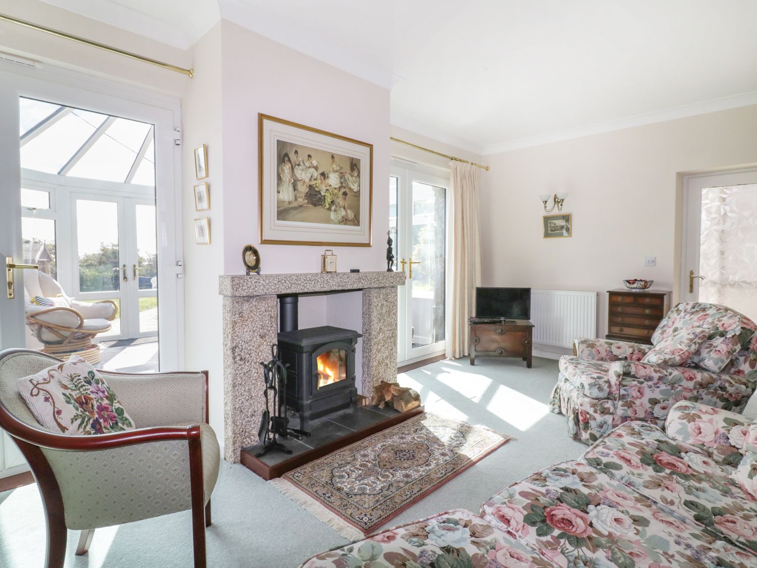 A living room with a fireplace armchairs and a floral sofa at Sheilas Cottage in Penryn