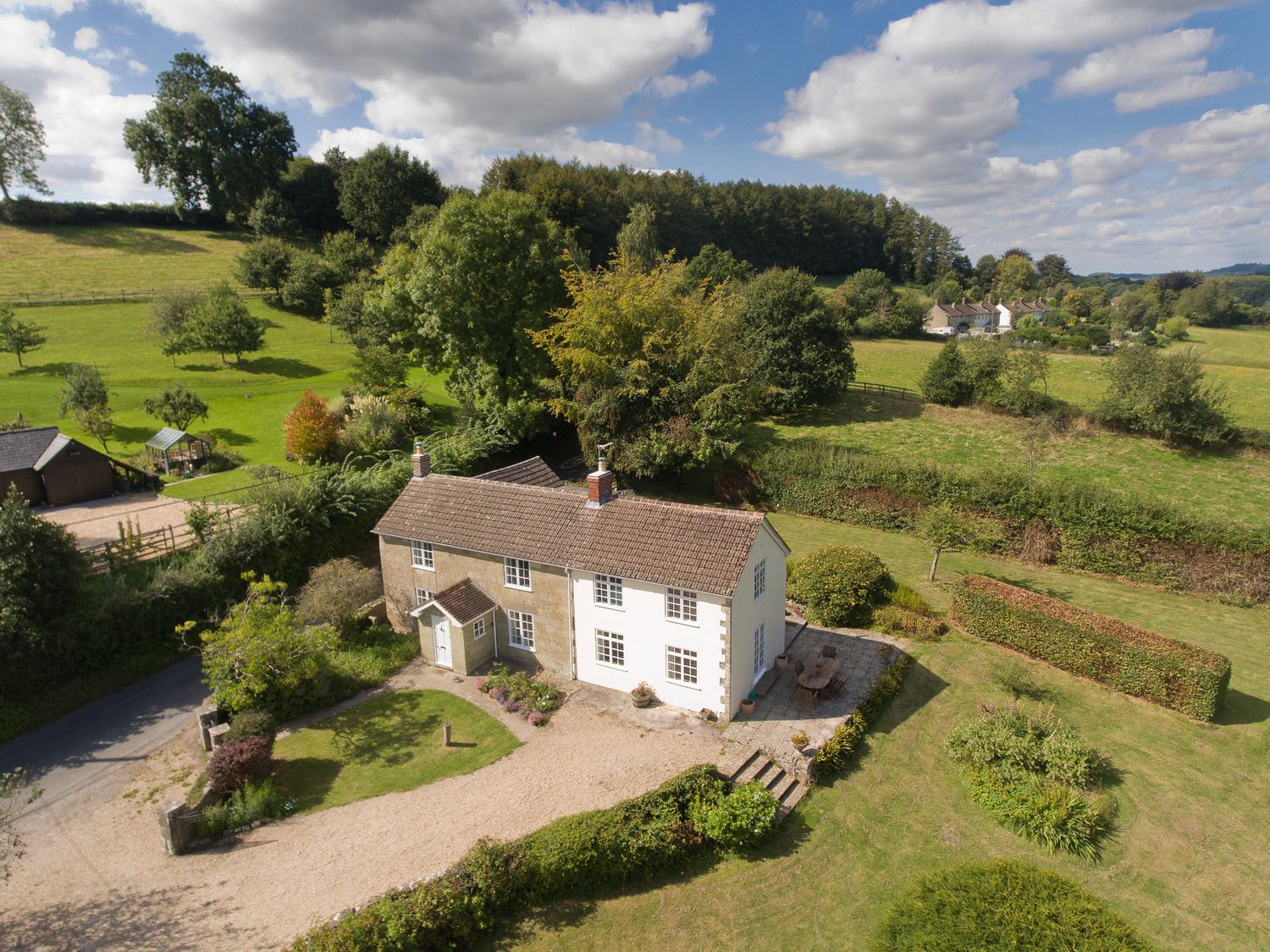 An aerial view of a countryside house with a gravel driveway garden and surrounding trees at Church View in Salisbury
