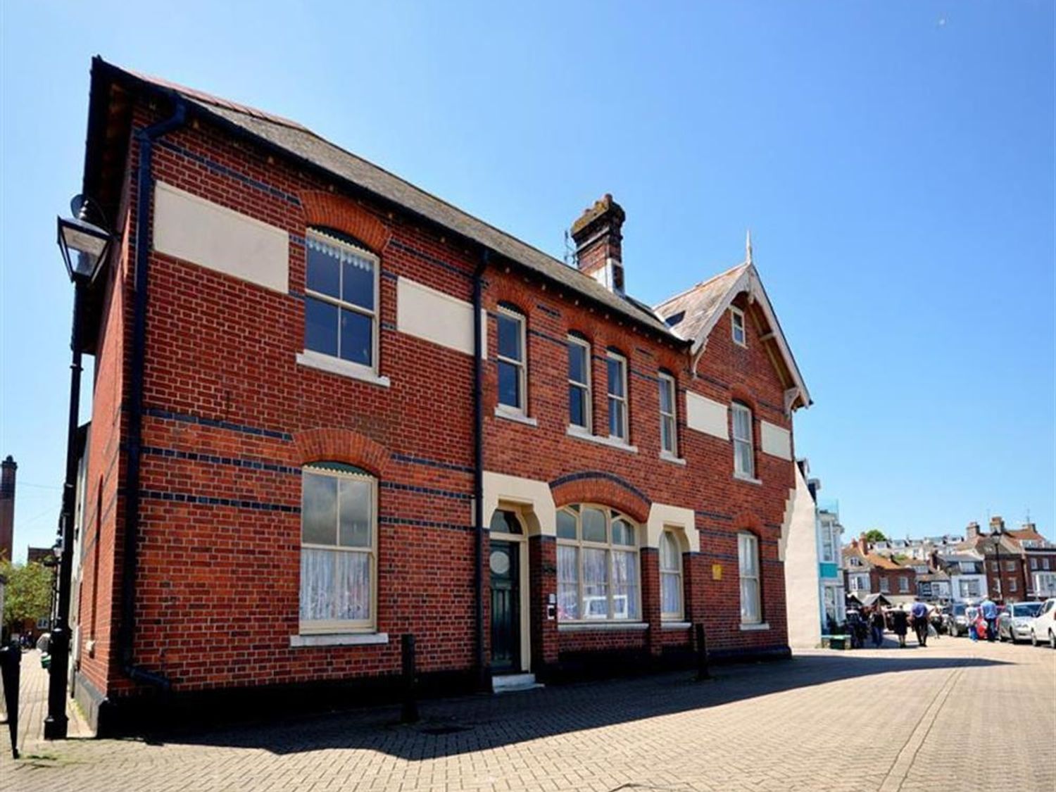 A two story brick building with multiple windows on a paved street at Mutiny House in Brewers Quay Harbour