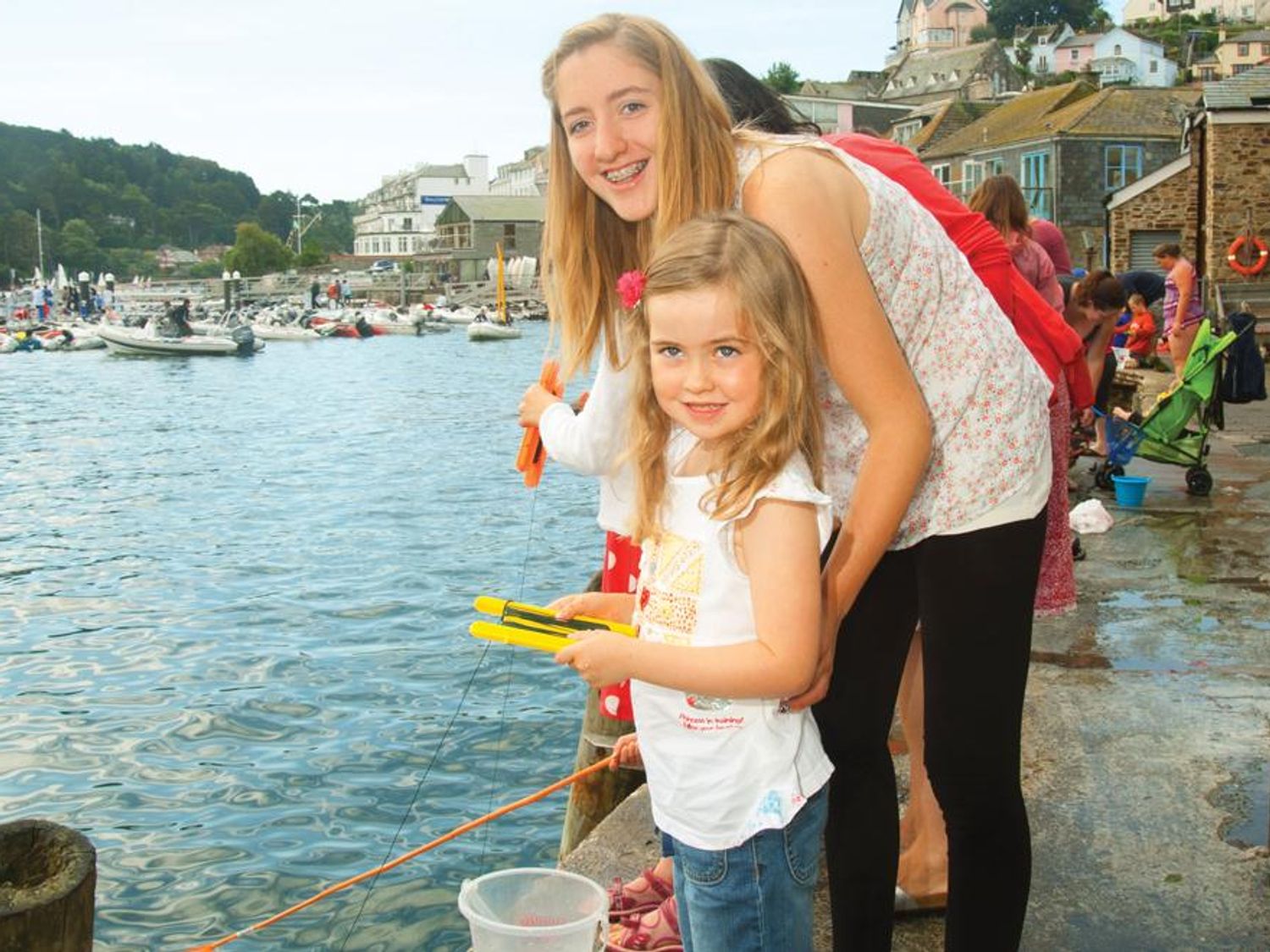 Children fishing with rods by the water near boats and buildings at 3 Combehaven Salcombe