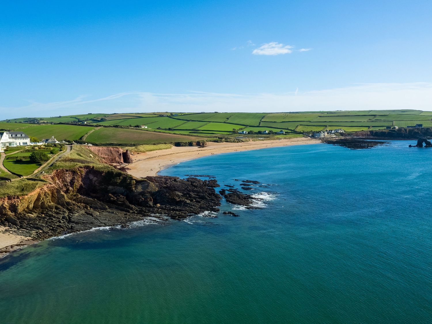 A coastal landscape with cliffs green fields and a sandy beach at Savernake in Thurlestone