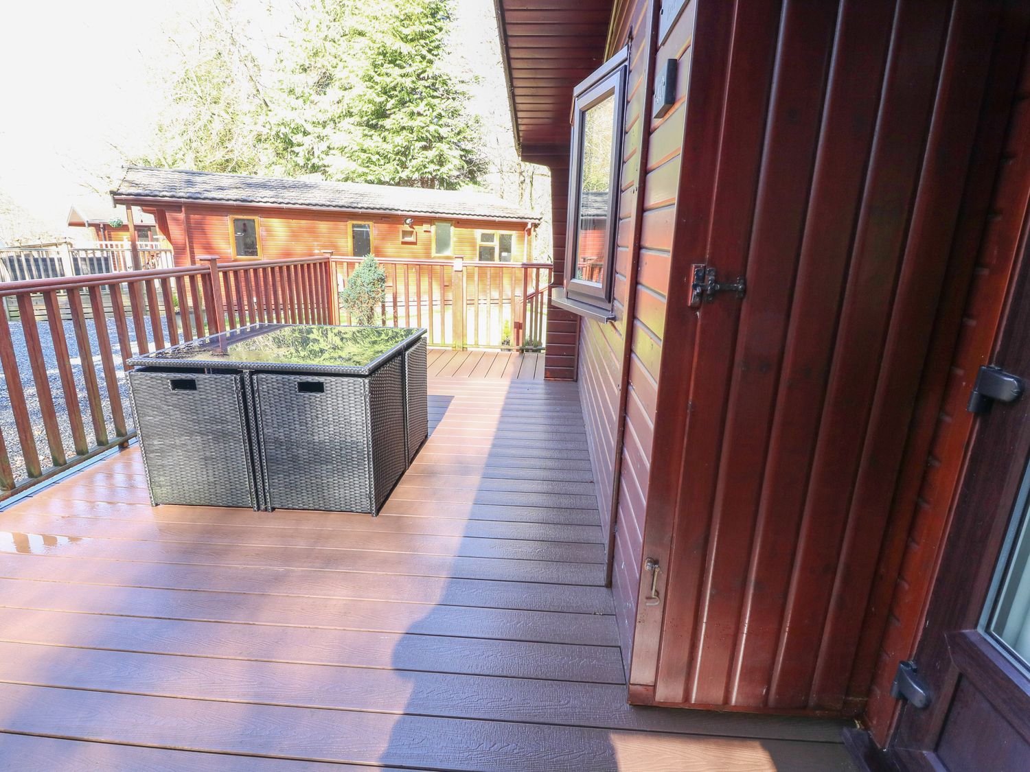 An outdoor wooden deck with a rattan table and chairs near a wooden cabin at 40 Skiptory Howe in Troutbeck Bridge