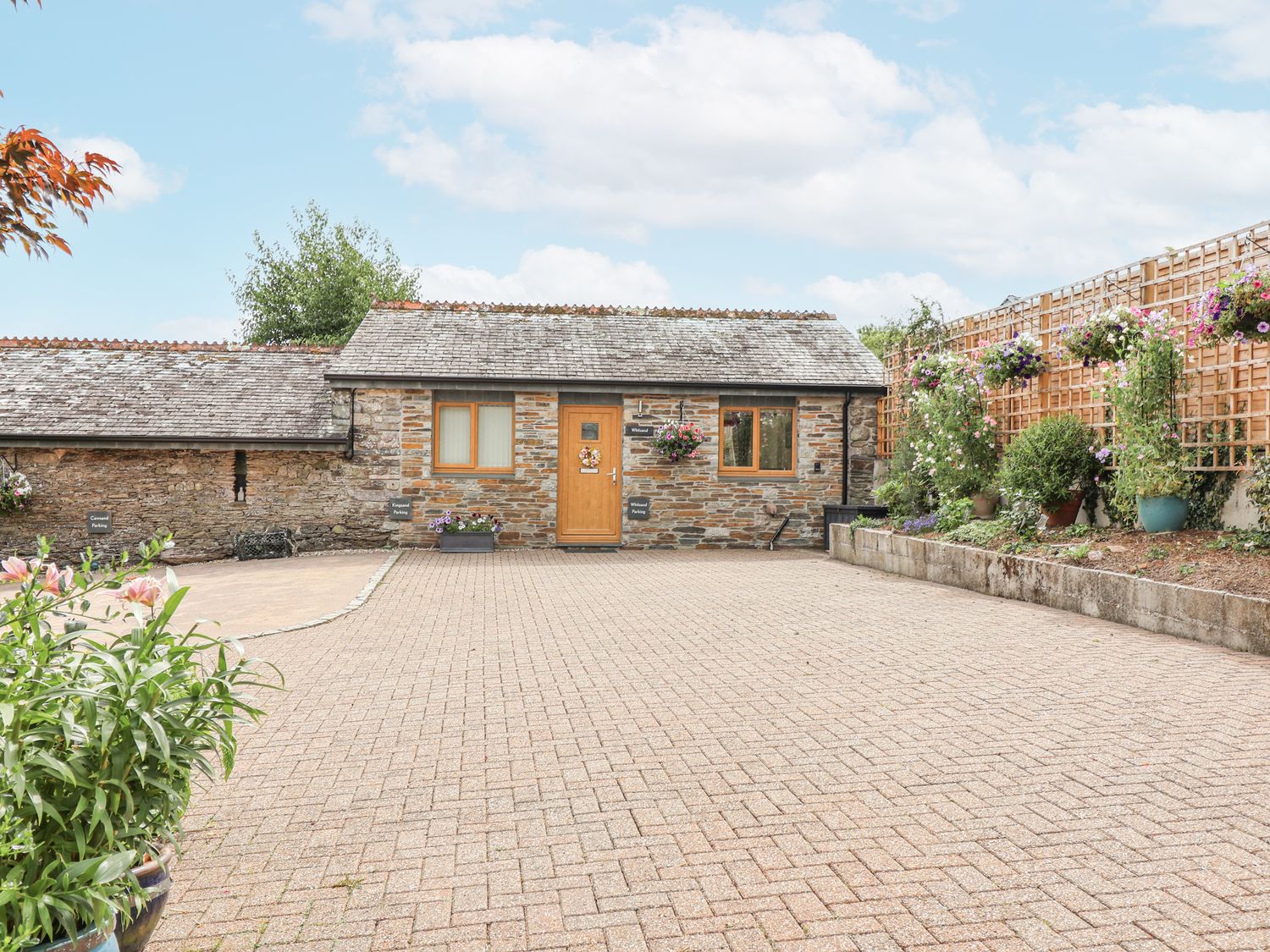 An outdoor area with a stone building and flower pots at Whitsand in Tideford