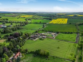 An aerial view of a farm surrounded by fields and trees at Sykes Lodge Malton