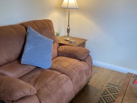 A sofa with a cushion and a lamp on a table at Daffodil Lodge Saltburn-by-the-Sea