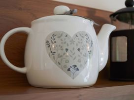 A teapot with floral design on a kitchen shelf at Daffodil Lodge Saltburn-by-the-Sea