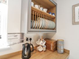 A kitchen with a kettle and shelves of dishes at Chapel Cottage in Filey