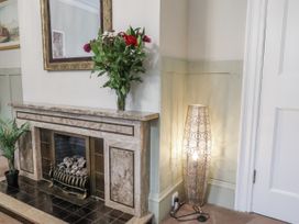 A living room with a fireplace and flowers on a table at The Manor House in Scarborough