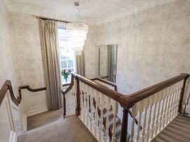 A staircase with a chandelier and mirror in the hallway at The Manor House in Scarborough